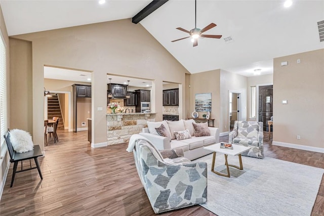 living area with high vaulted ceiling, beam ceiling, baseboards, and wood finished floors