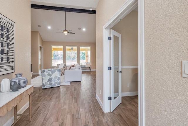 interior space with ceiling fan, a textured wall, wood finished floors, and baseboards