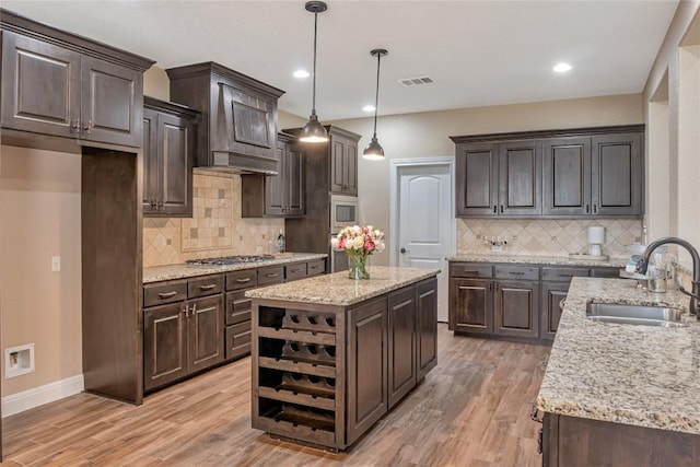 kitchen featuring stainless steel appliances, a sink, visible vents, light wood-style floors, and dark brown cabinets