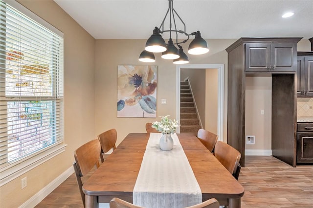 dining area with recessed lighting, light wood-style flooring, a chandelier, baseboards, and stairs