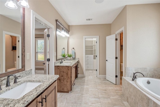 bathroom featuring a garden tub, visible vents, a sink, and toilet