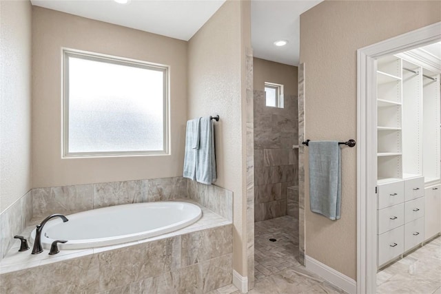 bathroom featuring a garden tub, a spacious closet, and a walk in shower