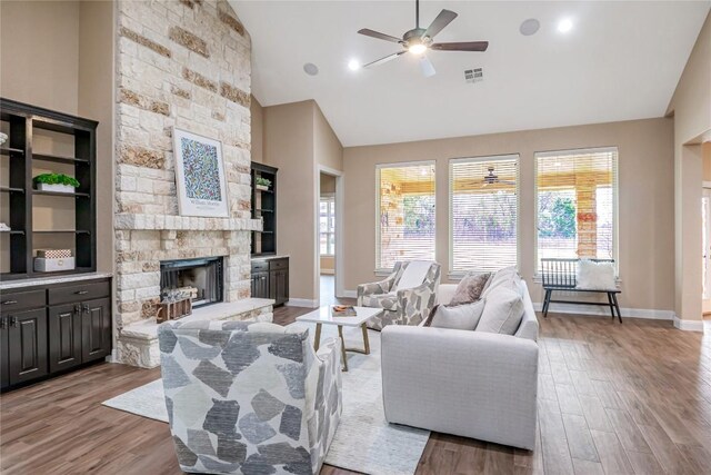 living area featuring high vaulted ceiling, a fireplace, and wood finished floors