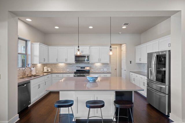 kitchen featuring white cabinetry, stainless steel appliances, decorative light fixtures, and sink