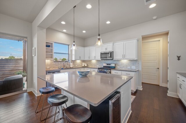 kitchen featuring a center island, stainless steel appliances, dark hardwood / wood-style floors, and beverage cooler