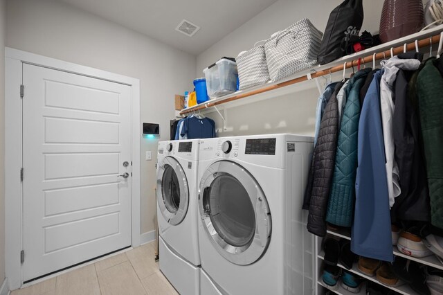 laundry area with independent washer and dryer and light tile patterned floors