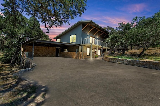 property exterior at dusk with a carport, driveway, and a balcony