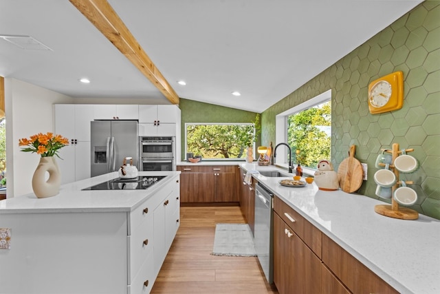 kitchen featuring vaulted ceiling with beams, white cabinetry, light hardwood / wood-style flooring, and stainless steel appliances