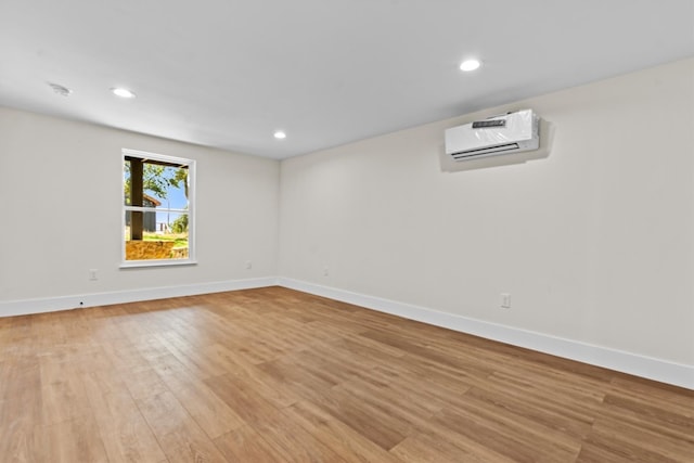 unfurnished room with an AC wall unit and light hardwood / wood-style flooring