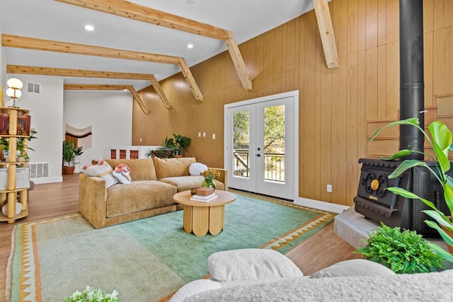 living room with hardwood / wood-style flooring, wood walls, a wood stove, french doors, and lofted ceiling with beams