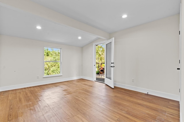 unfurnished room with lofted ceiling with beams and light hardwood / wood-style flooring