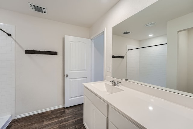 bathroom with wood-type flooring, vanity, and a tile shower