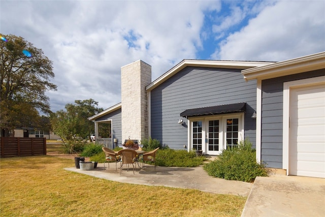 rear view of property featuring a patio area, a lawn, and a garage