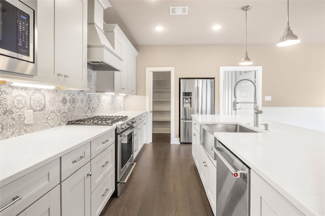 kitchen with hanging light fixtures, stainless steel appliances, custom exhaust hood, white cabinets, and dark hardwood / wood-style flooring