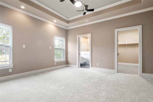 unfurnished bedroom with a spacious closet, ornamental molding, multiple windows, and ceiling fan