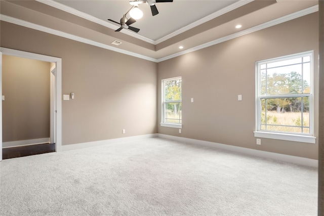 carpeted spare room with crown molding, a healthy amount of sunlight, a tray ceiling, and ceiling fan