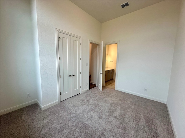 unfurnished bedroom featuring ensuite bath and light carpet