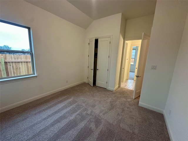 carpeted empty room featuring vaulted ceiling