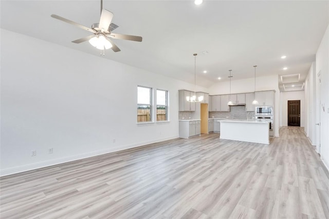 unfurnished living room with baseboards, lofted ceiling, ceiling fan with notable chandelier, light wood-type flooring, and recessed lighting