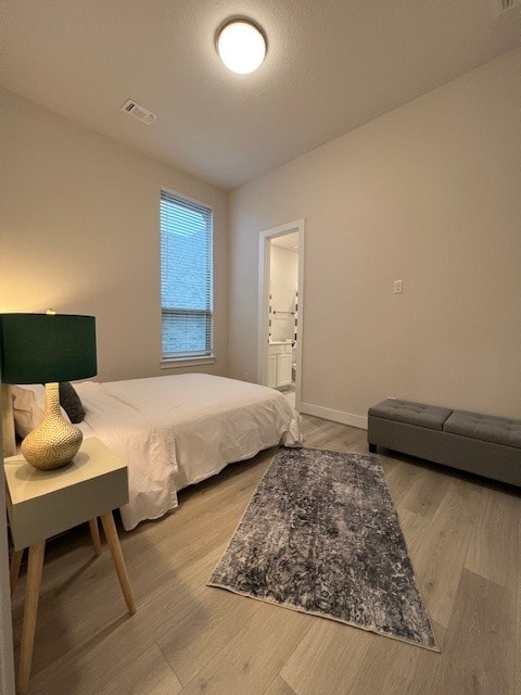 bedroom featuring connected bathroom and hardwood / wood-style flooring