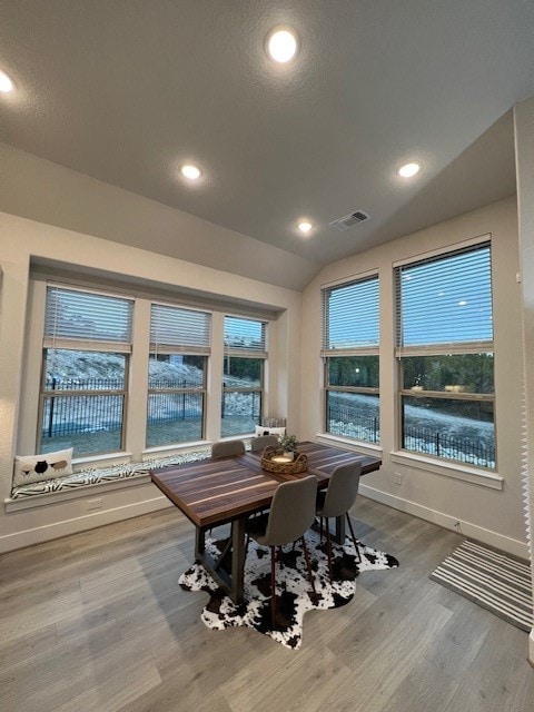 dining area featuring a wealth of natural light, lofted ceiling, and hardwood / wood-style flooring