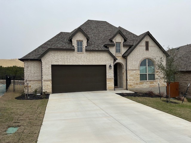 french country style house with a front lawn and a garage