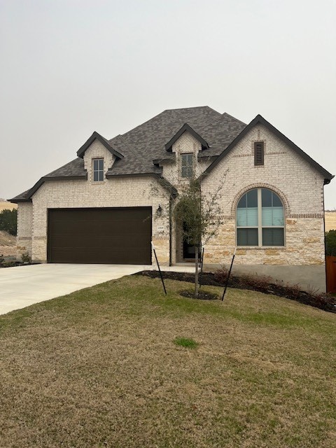 french provincial home featuring a front yard and a garage