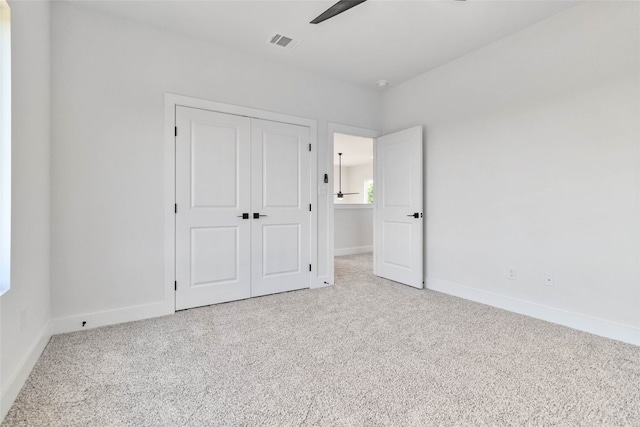 unfurnished bedroom featuring a closet, light colored carpet, and ceiling fan