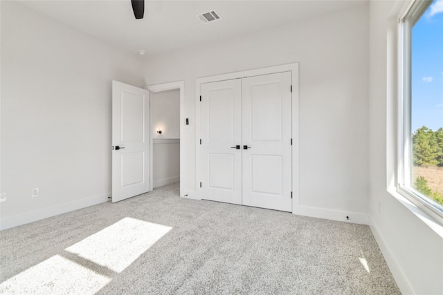 unfurnished bedroom with light carpet, a closet, and ceiling fan