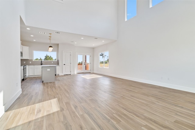 unfurnished living room with a towering ceiling and light hardwood / wood-style floors