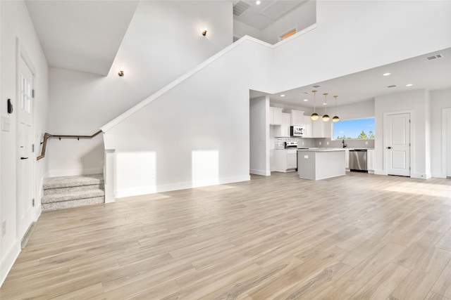 unfurnished living room featuring light hardwood / wood-style floors and a high ceiling