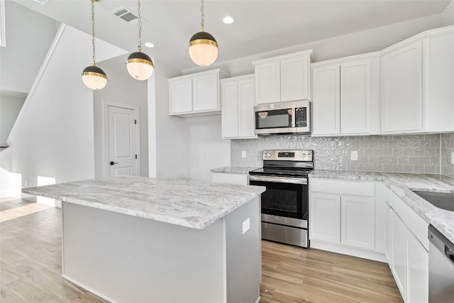 kitchen featuring light hardwood / wood-style flooring, white cabinets, hanging light fixtures, and stainless steel appliances