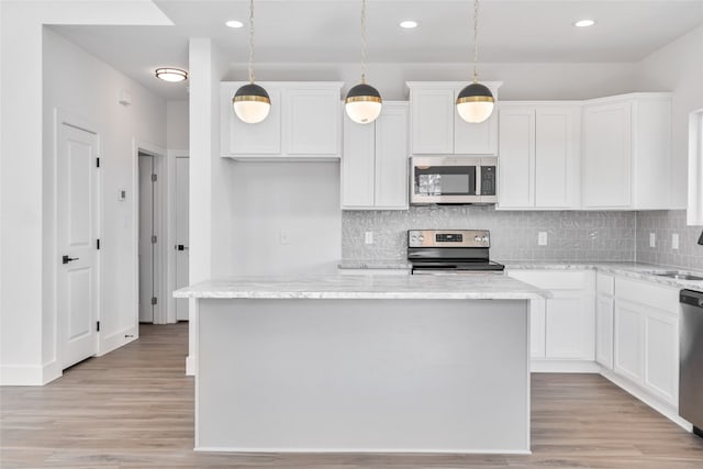 kitchen with hanging light fixtures, white cabinets, light wood-type flooring, appliances with stainless steel finishes, and light stone counters