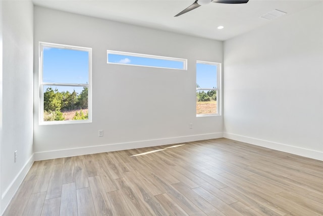 spare room with light hardwood / wood-style flooring, a wealth of natural light, and ceiling fan