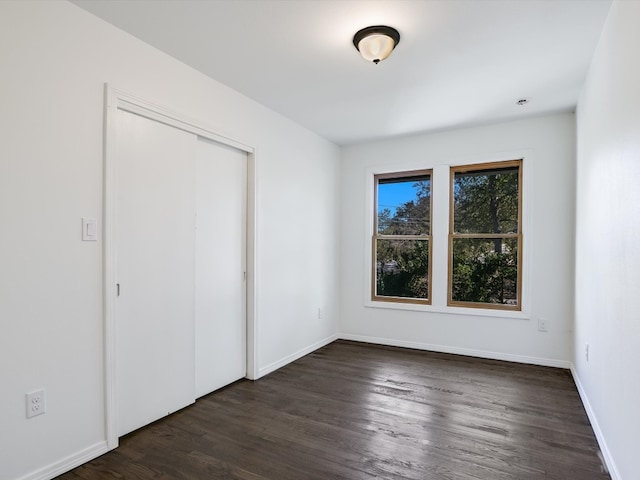 unfurnished bedroom featuring dark wood-type flooring and a closet