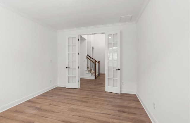 spare room featuring light wood-style floors, baseboards, ornamental molding, and french doors