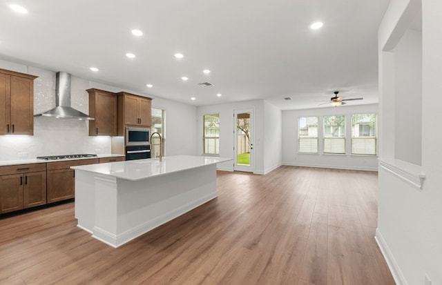 kitchen featuring oven, light countertops, wall chimney exhaust hood, and stainless steel gas stovetop