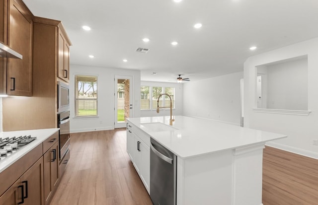 kitchen featuring visible vents, light countertops, a sink, light wood finished floors, and stainless steel appliances