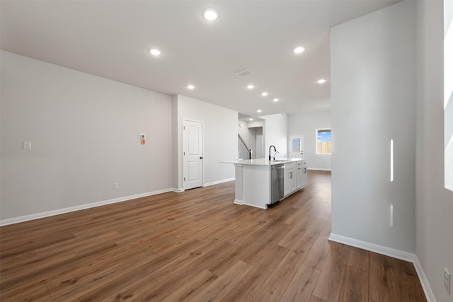 kitchen with dishwasher, a center island with sink, white cabinets, sink, and wood-type flooring