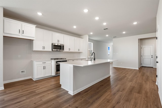 kitchen with white cabinets, stove, a center island with sink, and dark hardwood / wood-style floors