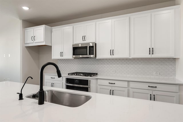 kitchen featuring decorative backsplash, sink, white cabinetry, and stainless steel appliances