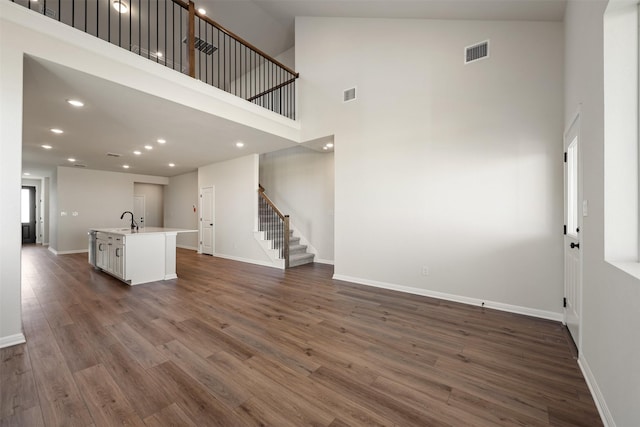 unfurnished living room with a high ceiling, dark hardwood / wood-style flooring, and sink