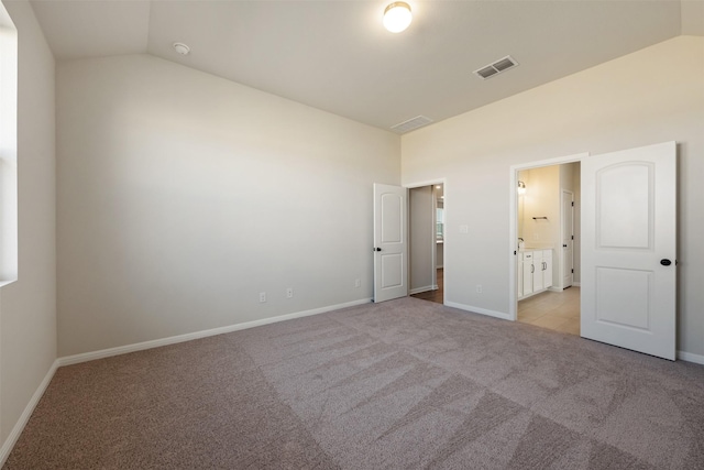 unfurnished bedroom with light carpet, connected bathroom, and lofted ceiling