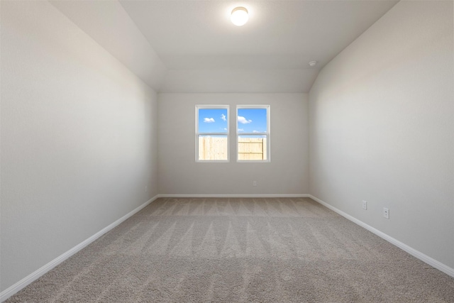 empty room featuring carpet and vaulted ceiling