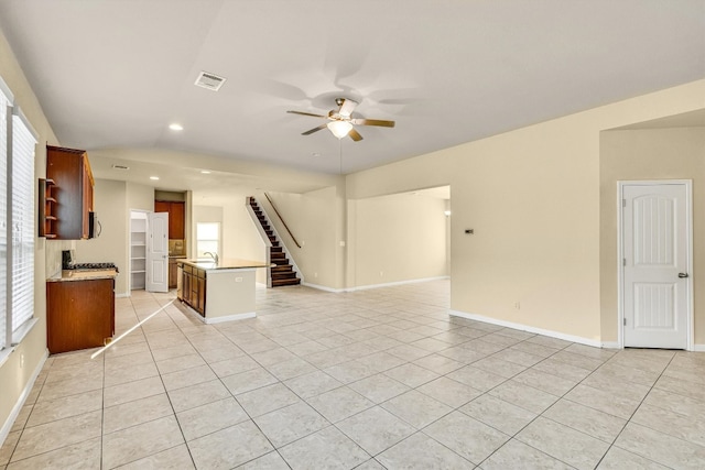 unfurnished living room with sink, light tile patterned floors, and ceiling fan