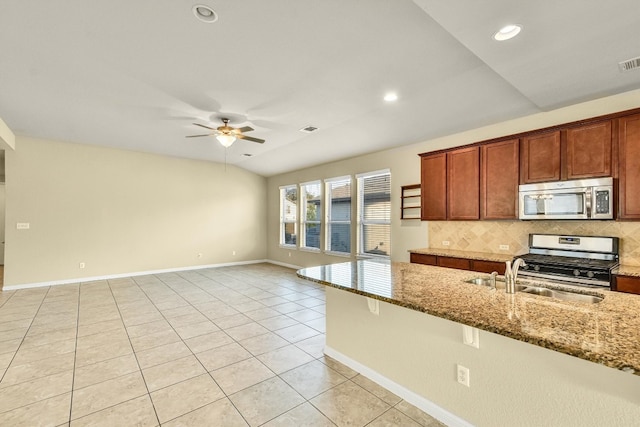 kitchen with ceiling fan, appliances with stainless steel finishes, backsplash, light stone countertops, and vaulted ceiling