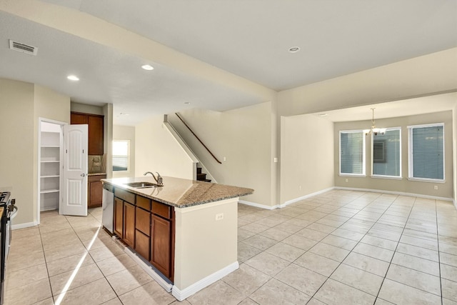 kitchen with a kitchen island with sink, light stone countertops, a notable chandelier, light tile patterned floors, and appliances with stainless steel finishes