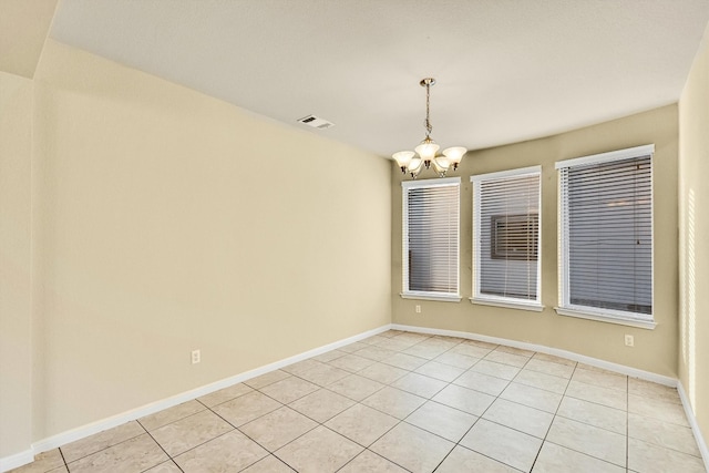 tiled empty room featuring a notable chandelier