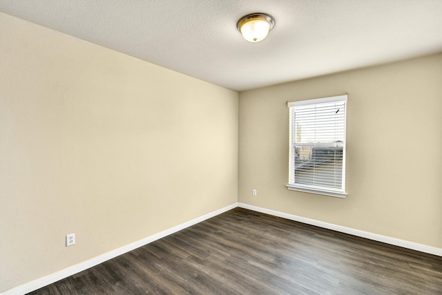 unfurnished room with a textured ceiling and dark wood-type flooring