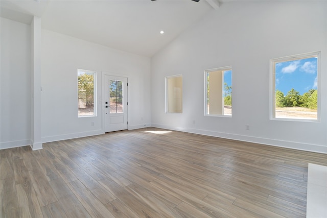 interior space featuring light hardwood / wood-style floors, ceiling fan, high vaulted ceiling, and beamed ceiling